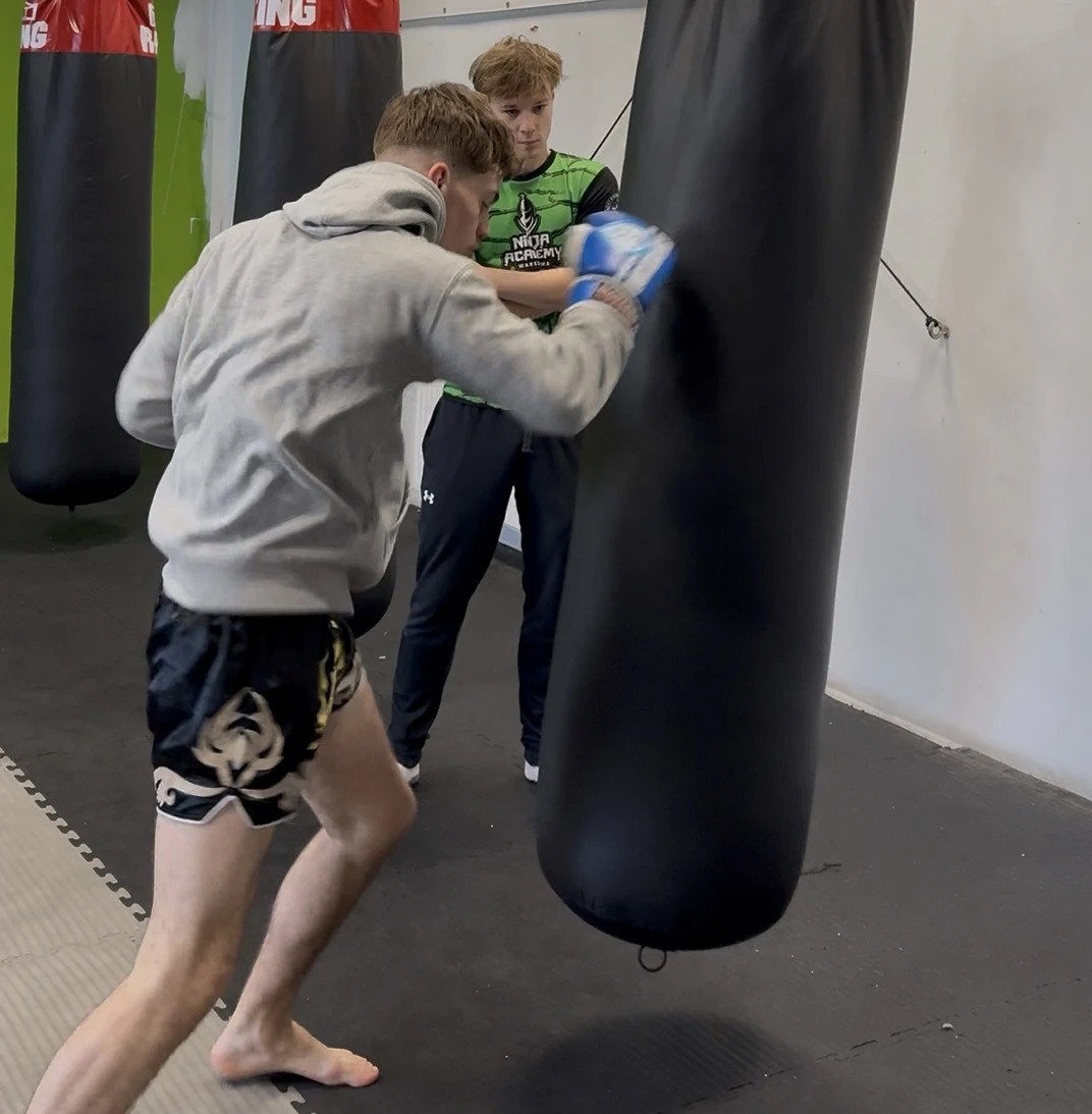 Aleks Szulc coaching a client on heavy bag technique at Ninja Academy Warszawa
